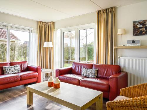 a living room with red leather couches and a table at Holiday Home Bungalowpark It Wiid by Interhome in Eernewoude