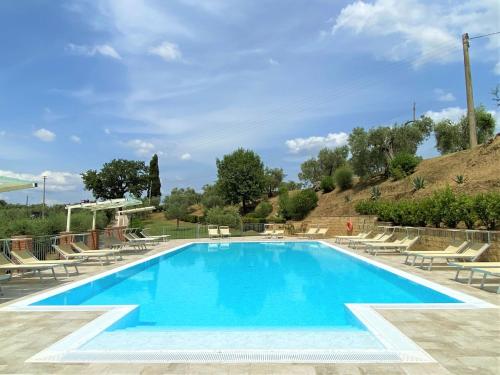 una grande piscina con sedie a sdraio e sedie intorno ad essa di Apartment Stregaia-5 by Interhome a Montaperti