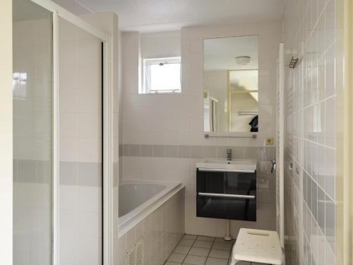 a bathroom with a tub and a sink and a mirror at Holiday Home Bungalowpark It Wiid in Eernewoude