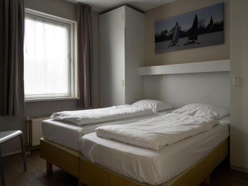 zwei Einzelbetten in einem Zimmer mit Fenster in der Unterkunft Holiday Home Bungalowpark It Wiid by Interhome in Eernewoude
