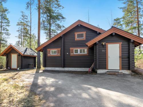 een zwart huis met een witte deur en een garage bij Holiday Home Villa virkeä by Interhome in Vierumäki