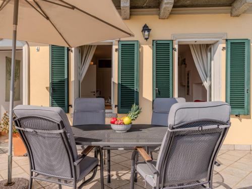 a table with chairs and an umbrella on a patio at Apartment La Pianca-4 by Interhome in Musso