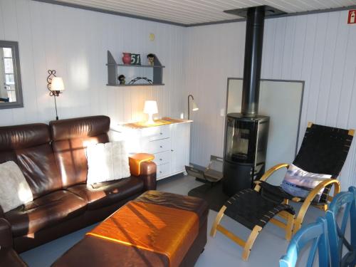 salon ze skórzaną kanapą i piecem opalanym drewnem w obiekcie Chalet Thorabu - SOW117 by Interhome w mieście Øyuvstad