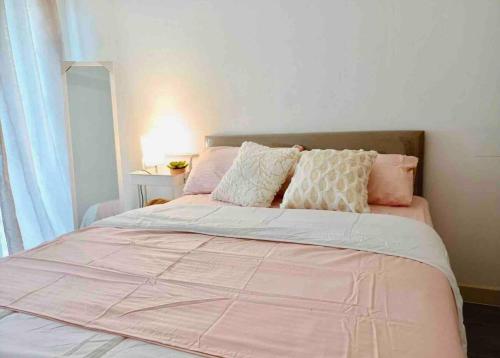 a bed with a pink comforter and pillows at Tranquil in Manila