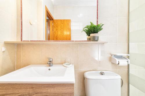 uma casa de banho com um lavatório, um WC e um espelho. em Bungalow Green Oasis Club em Maspalomas