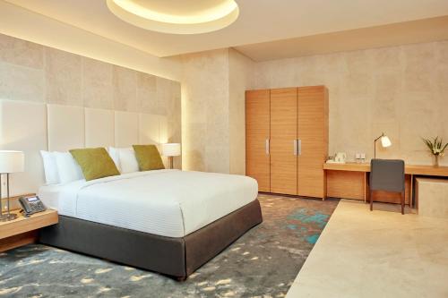 a bedroom with a large bed and a desk and a desk at Aerotel Muscat - Airport Transit Hotel in Muscat