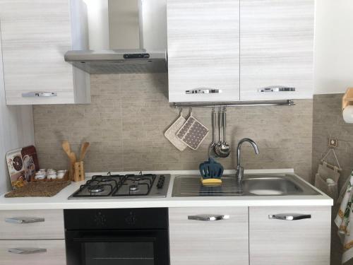 a white kitchen with a stove and a sink at CASA VACANZE ZOE - Terra in Serrano