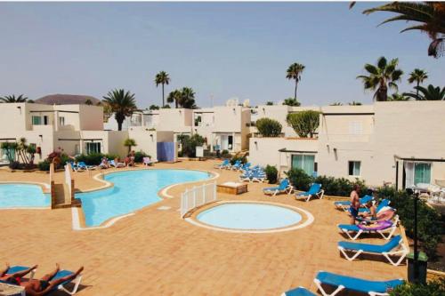 a resort with a pool and chairs and palm trees at Alisios Playa, pool view in Corralejo