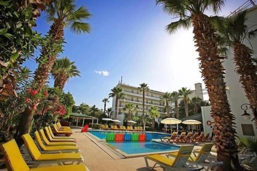 a resort with chairs and a swimming pool with palm trees at MALİBU RESORT in Kemer