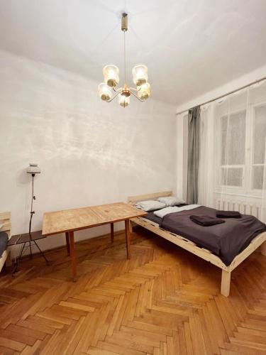 ein Schlafzimmer mit einem Bett, einem Tisch und einem Kronleuchter in der Unterkunft Cozy studio in Cracow in Krakau
