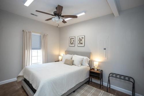 1 dormitorio con cama blanca y ventilador de techo en Cozy Cottage Whot Tub Near Ft Leonard Wood! en Waynesville