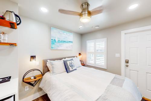 1 dormitorio con 1 cama blanca y ventilador de techo en Beach 5 Villas #B4, en Fernandina Beach