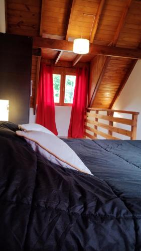 a bedroom with a black bed with red curtains at LOS ABEDULES in El Bolsón