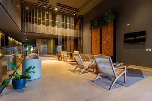 a lobby with chairs and tables in a building at Hotel Cassino Tower Curitiba Aeroporto By Nacional Inn in São José dos Pinhais