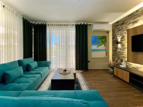 a living room with a blue couch and a tv at EKA Luxury Seaview Apartments in Vlorë
