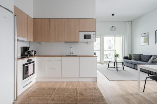 a kitchen with white cabinets and a living room at 2ndhomes Tampere "Puistotie" Apartment - 2BR Apt with Sauna and Balcony at Tammela Stadium in Tampere