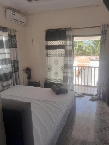 a bedroom with a bed and a window with a balcony at Smile Gambia Beach Bar in Brufut