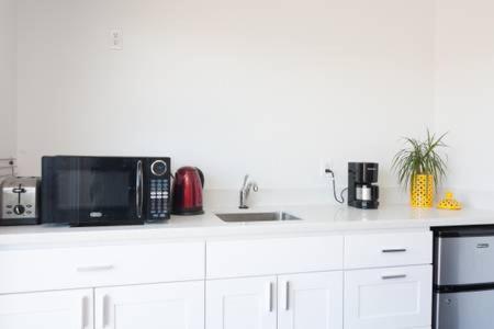 Una cocina blanca con microondas y fregadero. en Modern studio near UCSF/Chase/Oracle Park, en San Francisco