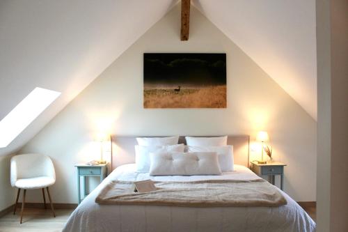 a bedroom with a bed with white sheets and pillows at Maison Moz in Fontaines-en-Sologne