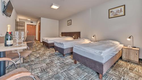 a hotel room with three beds and a table and chairs at St Lukas Medical & SPA in Świeradów-Zdrój