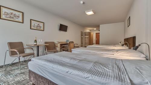 a bedroom with two beds and a table and chairs at St Lukas Medical & SPA in Świeradów-Zdrój
