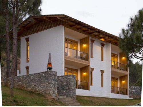 a large white house with windows and a stone wall at Dhensa Resort in Punākha