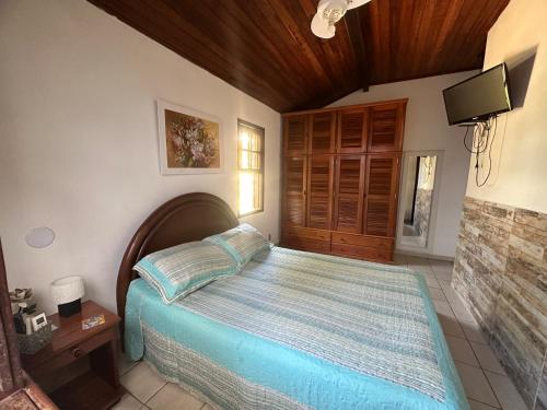 1 dormitorio con 1 cama y TV. en Búzios Geribá 2 minutos a pé da praia, en Búzios