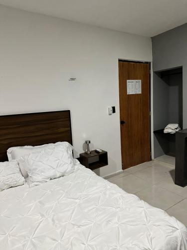 a bedroom with a white bed and a wooden door at Apartamentos 31 in Progreso