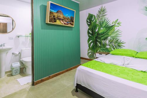 1 dormitorio con cama y pared verde en NOMADA HOTEL GUATAPE, en Guatapé