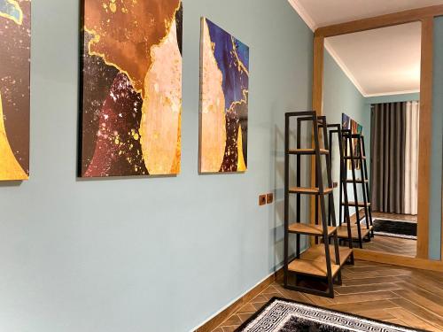 a room with four paintings on a wall with a ladder at EKA Luxury Seaview Apartments in Vlorë