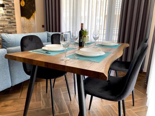 a wooden table with plates and wine glasses on it at EKA Luxury Seaview Apartments in Vlorë