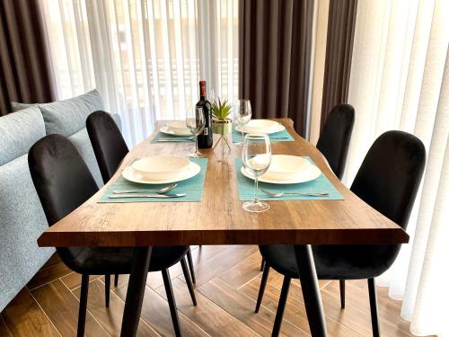 a wooden table with chairs and a bottle of wine at EKA Luxury Seaview Apartments in Vlorë