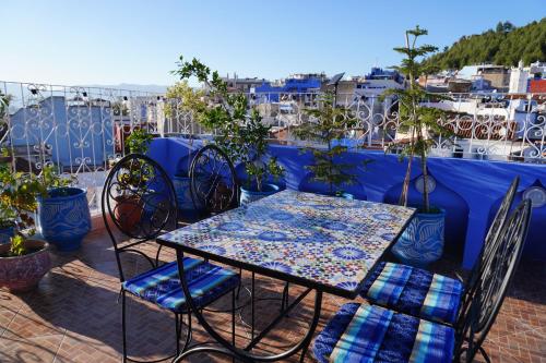 une table et des chaises assises sur un balcon dans l'établissement RIAD CHENGLI 蓝城里, à Chefchaouen