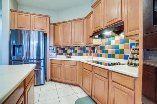 a kitchen with wooden cabinets and a stainless steel refrigerator at Group Getaway with Pool and Putting Green in Goodyear in Goodyear