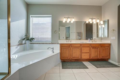 a bathroom with a tub and a sink and a mirror at Group Getaway with Pool and Putting Green in Goodyear in Goodyear