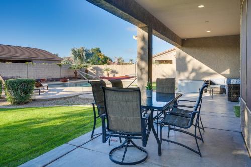 a patio with a table and chairs and a yard at Group Getaway with Pool and Putting Green in Goodyear in Goodyear