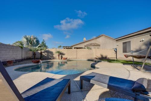 a swimming pool with benches in a backyard at Group Getaway with Pool and Putting Green in Goodyear in Goodyear