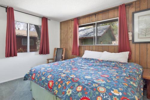 a bedroom with a bed and two windows with red curtains at Nestled Oaks Cottage~ Bear Mountain Resort Chalet~ in Big Bear Lake