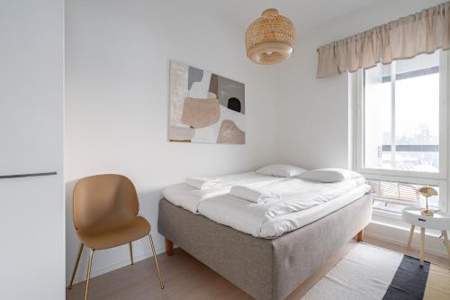 a bedroom with a bed and a chair and a window at 2ndhomes Tampere "Sonetti" Apartment - Modern 2BR Apartment with Sauna and Balcony in Tampere