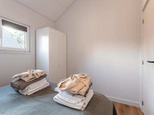 - une chambre avec des murs blancs et un lit avec des serviettes dans l'établissement Abs Blokhut, à Putten