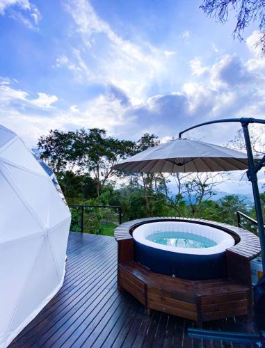 a hot tub on a deck with an umbrella at La Julita Glamping in La Mesa