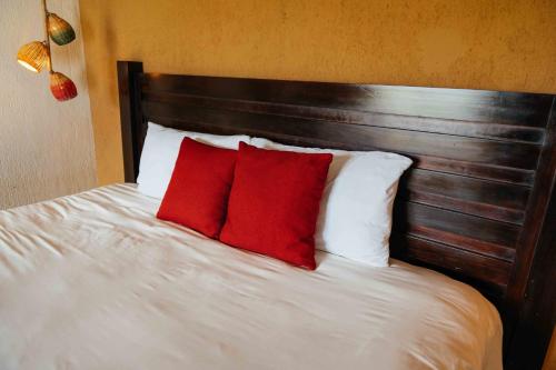 a large bed with two red pillows on it at Casa 1800 Ataco Hotel Boutique in Concepción de Ataco