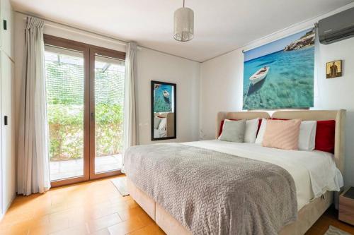 a bedroom with a bed and a large window at Private Garden Home next to the beach and market in Athens