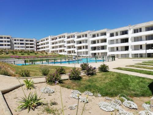 a large apartment building with a swimming pool in front of it at Condominio Miramar El Tabito in El Tabo