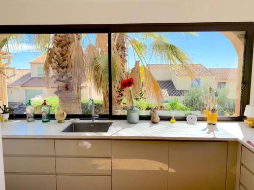 a kitchen counter with a sink and a large window at Charmante villa avec une âme. in Pignan