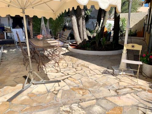 a patio with a table and chairs and an umbrella at Charmante villa avec une âme. in Pignan