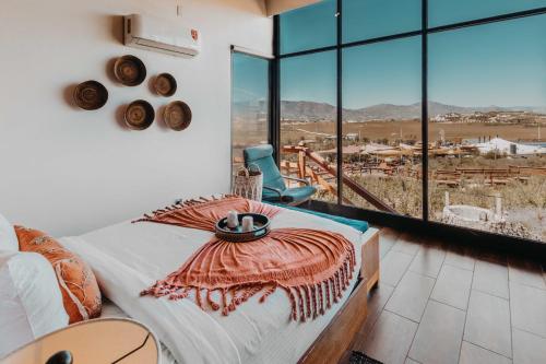 a bedroom with a bed and a chair and windows at Contemplacion Resort & Spa in Valle de Guadalupe