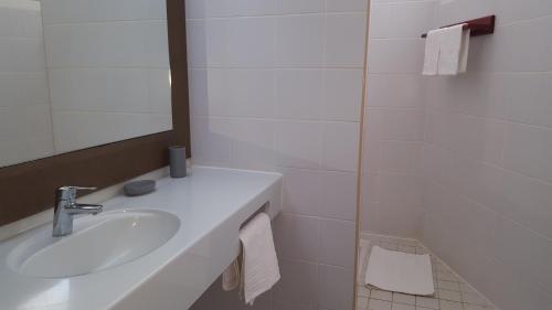 Baño blanco con lavabo y espejo en Le Cosy - Studio spacieux, équipé, proche Plage & Piscine, au Manganao en Saint-François