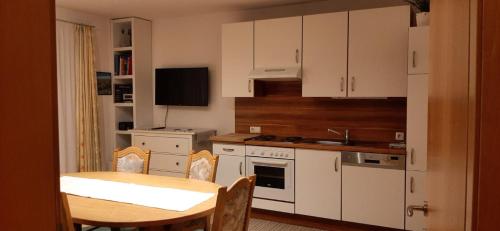 cocina con armarios blancos, mesa, mesa y sillas en Appartement Maurer, en Niederau