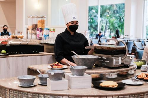 a chef wearing a mask in a kitchen preparing food at Hilton Colon Guayaquil Hotel in Guayaquil